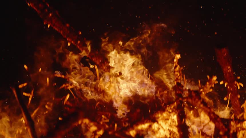 Closeup of branches on fire at night in slow motion