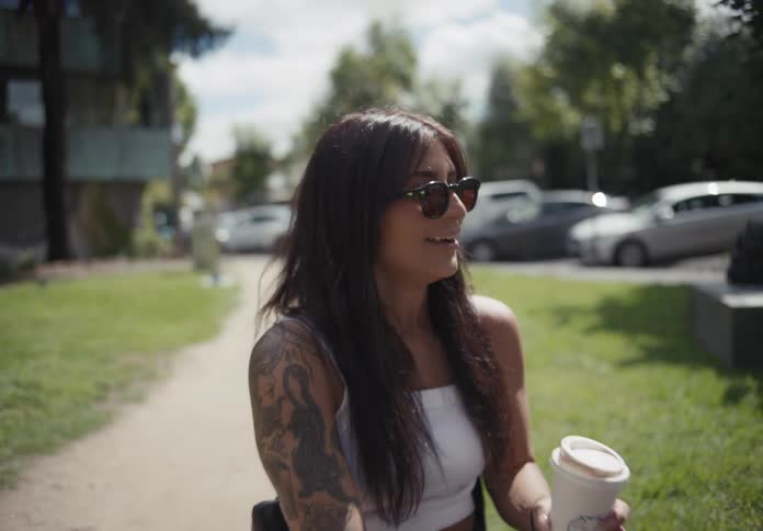Wheelchairbound woman holding a cup of coffee smiling and chatting in an outdoor setting