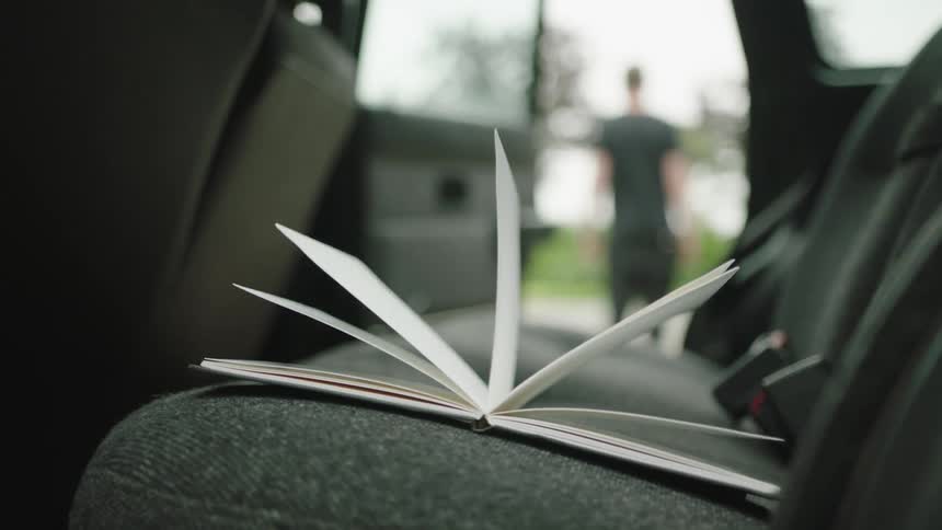 Closeup of an open book with pages flipping inside the back seat of a car