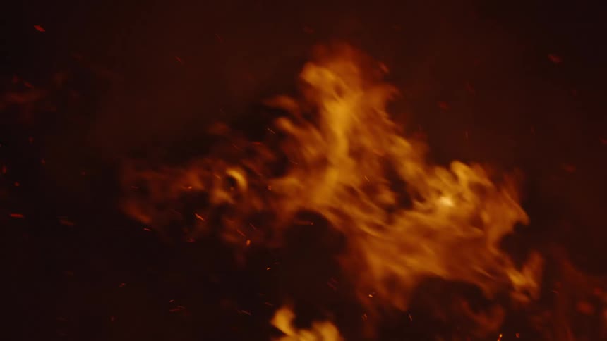 A fire that is going with the wind towards the left and several sparks and smoke go with it