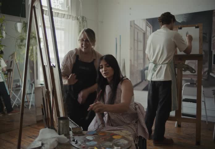 People and a wheelchair user painting on a canvas in an indoor room