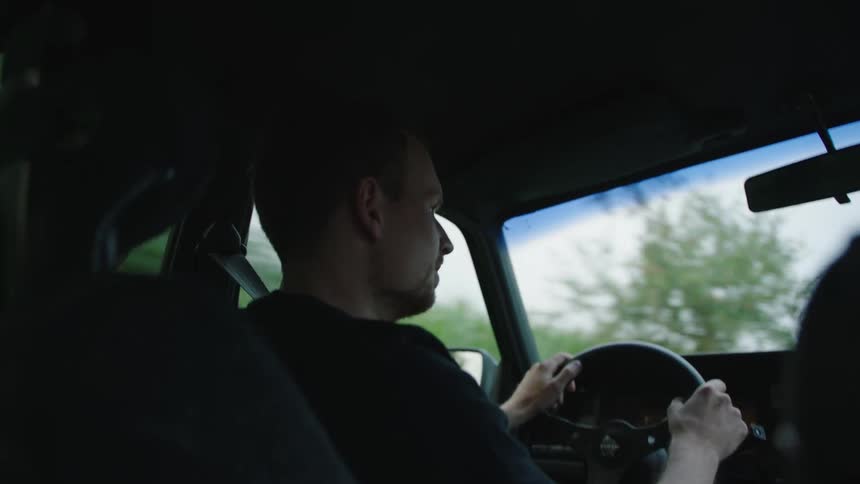 A man driving a small car through the countryside