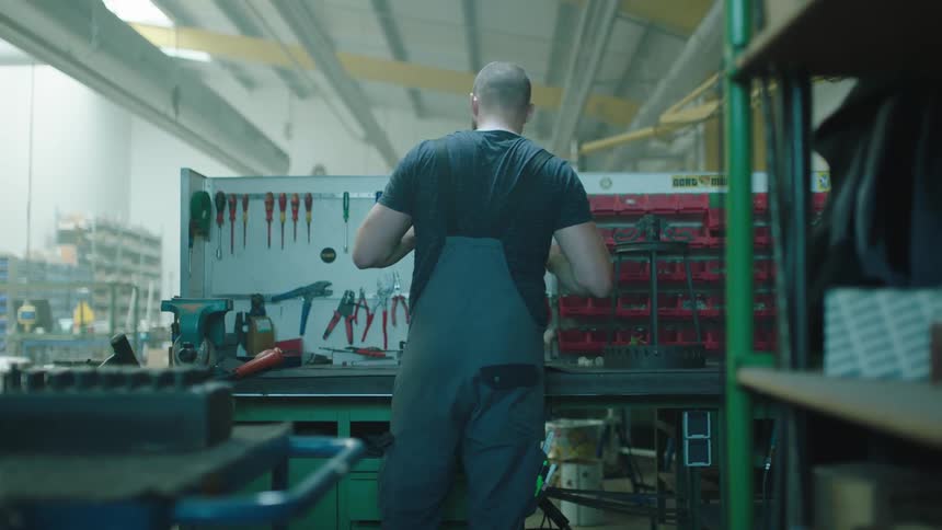 Man with his back to the camera in front of tools in an indoor setting