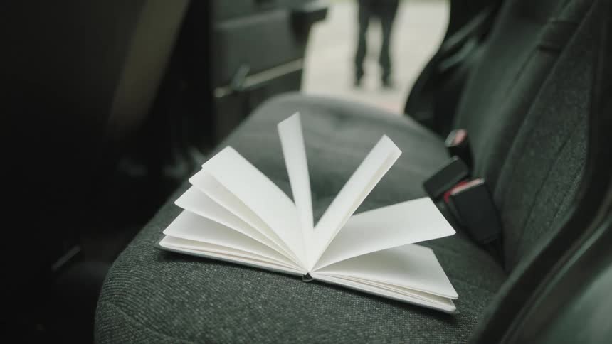 A small notebook with white pages on a car seat