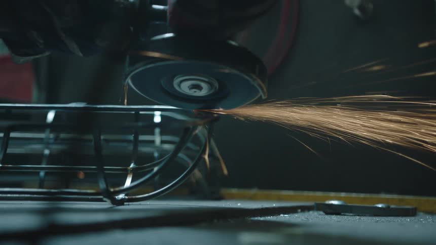 A circular cutting tool is rotating while cutting a metal object and gives off a lot of sparks