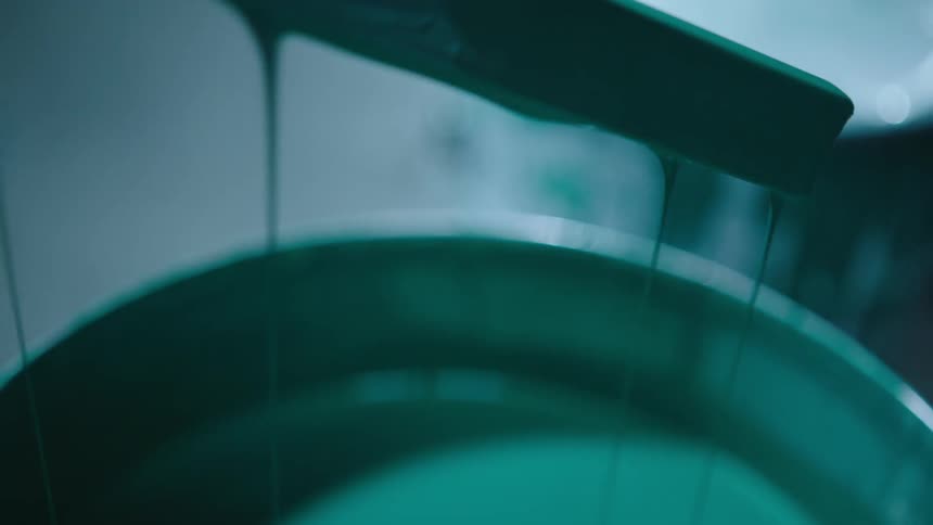 Metal rod with green paint falling into a bucket