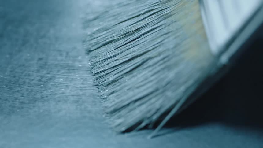 Close up of a brush painting a metallic surface