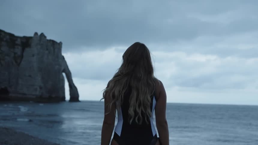 Woman with her back to the camera on the beach on a cloudy morning