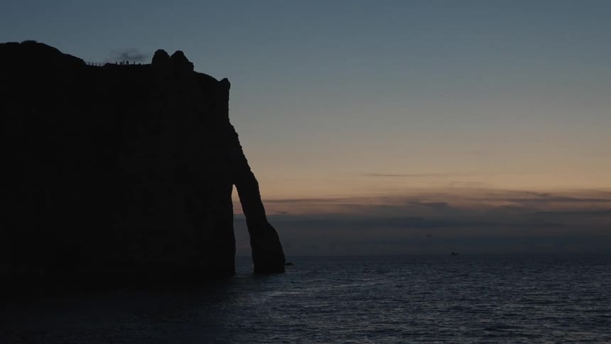A coastal mountain on a beach during dusk