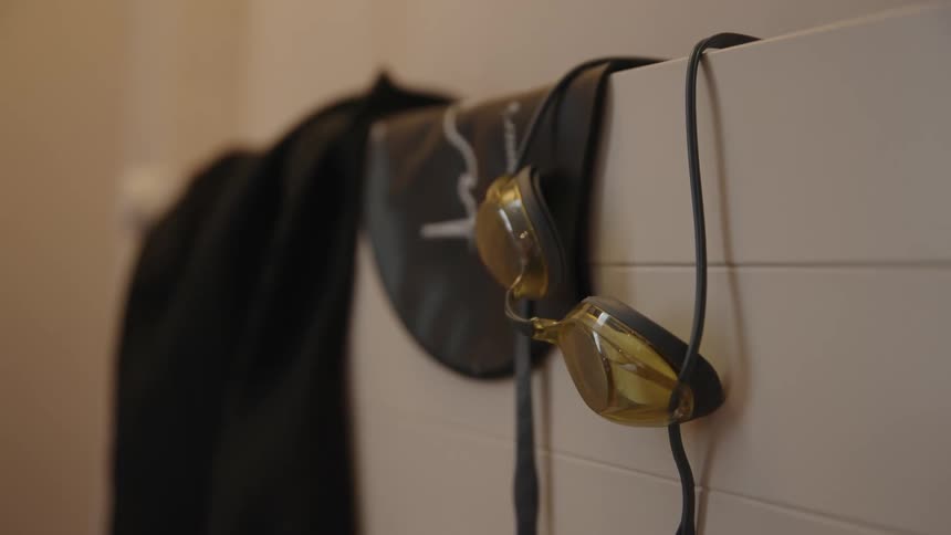 A swimming cap and goggles on top of a white tiled wall