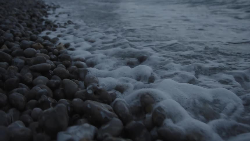 The sea waves break on the beach with small stones