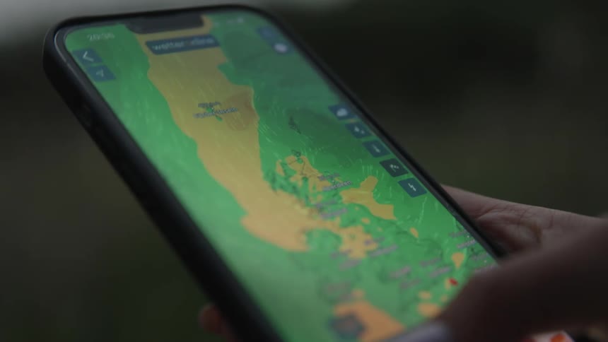 A hand checking a weather app on a smart phone