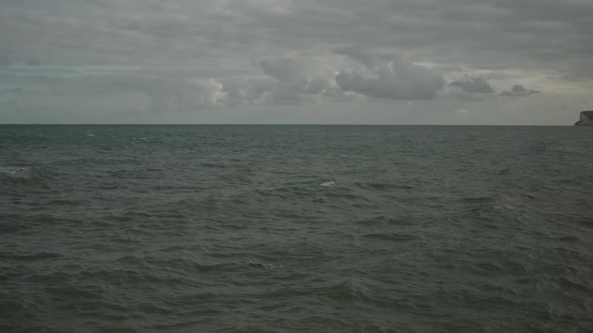 Woman swimming in the open sea against the tide on a cloudy day