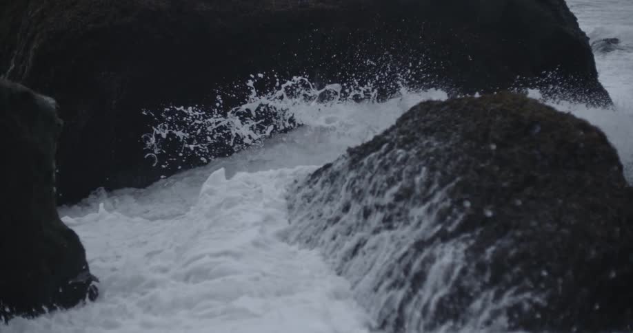 Waves crash against boulders on the shore