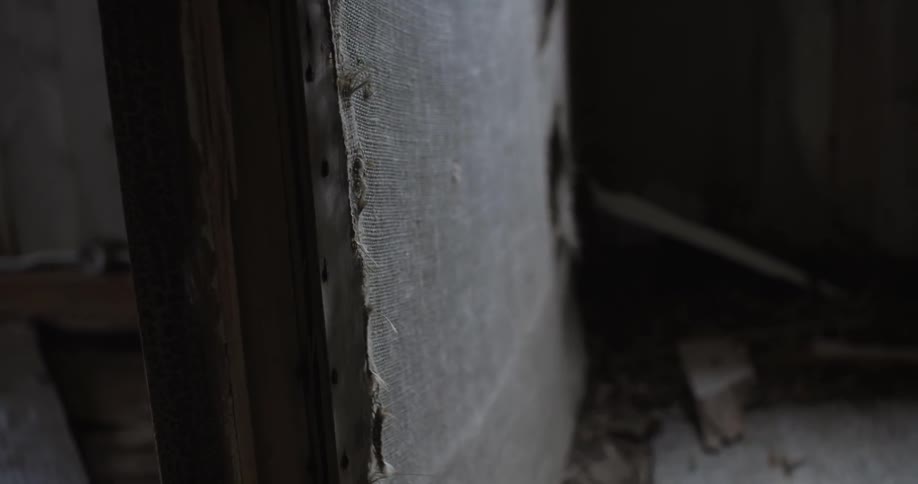 A piece of fabric that's come loose from a wall in a ruined building blows in the breeze