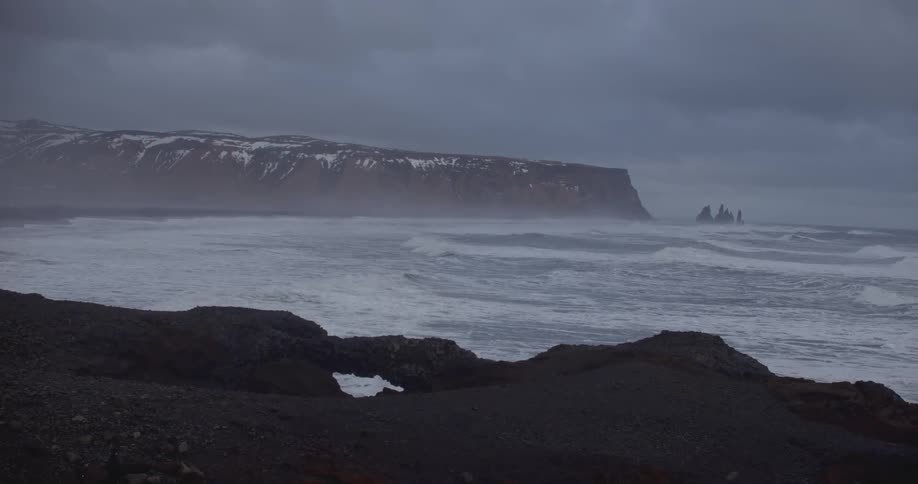 Waves come ashore beside a rocky cliff