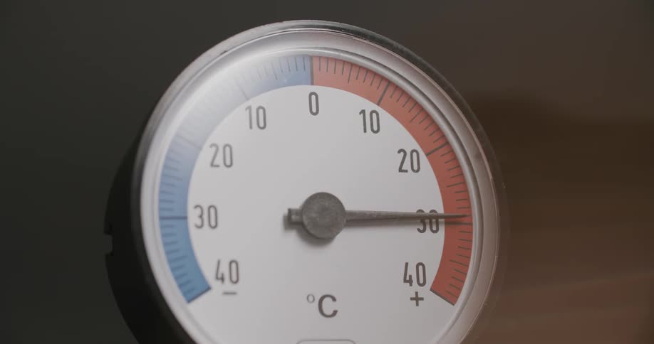 A closeup of a round thermometer showing an increase in temperature