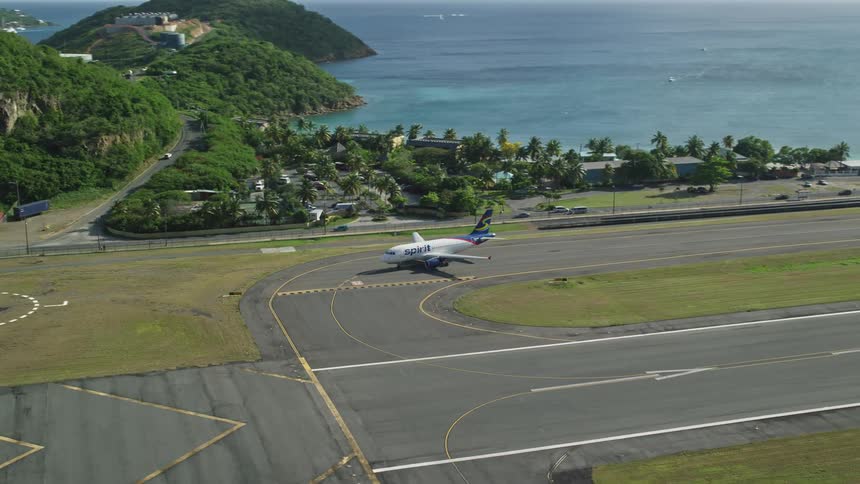 Aerial panorama of an airplane parked on the runway next to an ocean