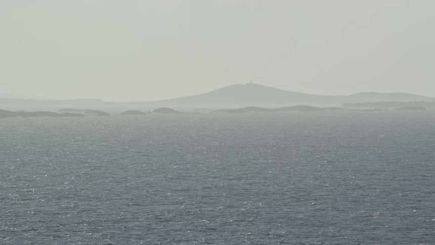 Ocean waves ripple mountain on horizon