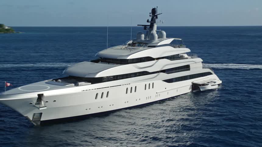 A large yacht sits off the coast of an island