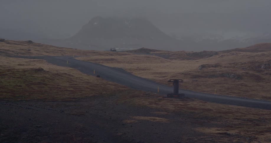 A truck travels down a windy hazy road