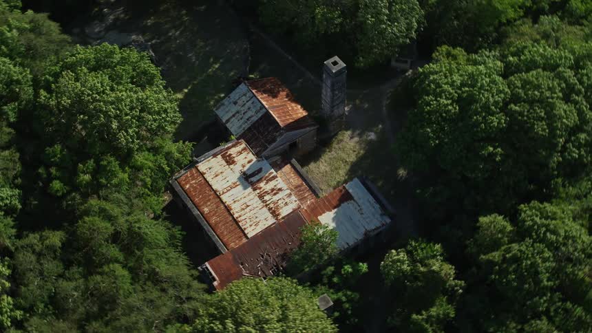 Aerial view of a ranch with a metal roof in the middle of a forest