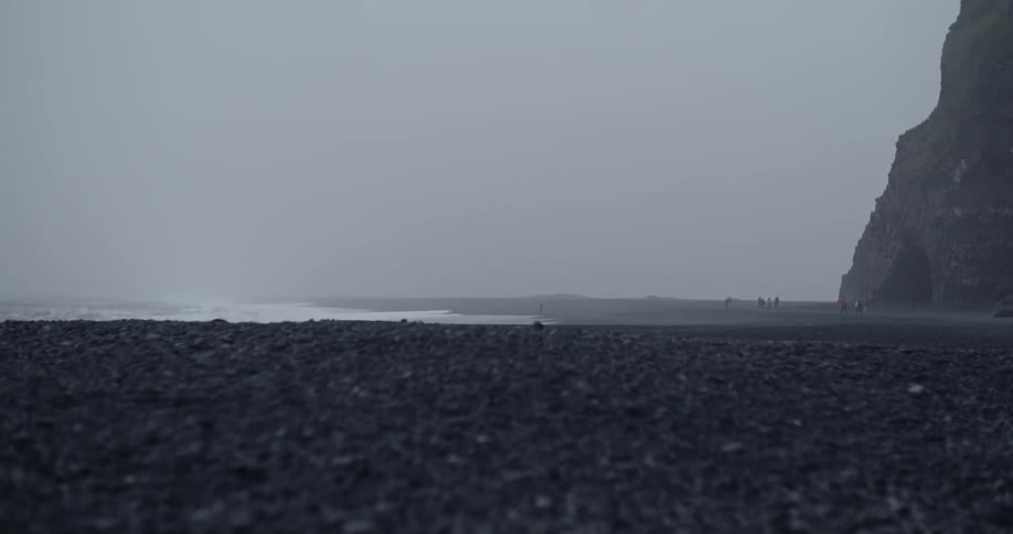 Waves crash into the cliffside shore on an overcast day
