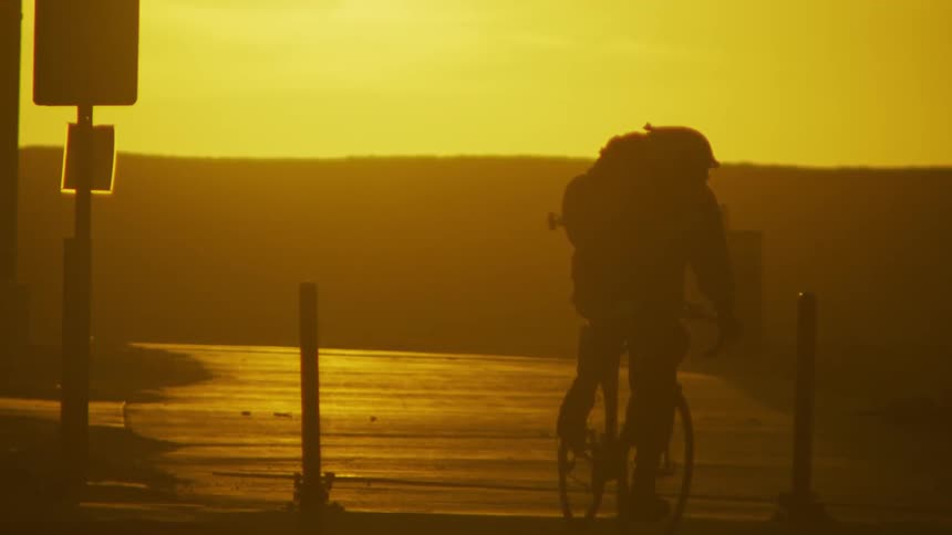 A bicyclist bikes down a road