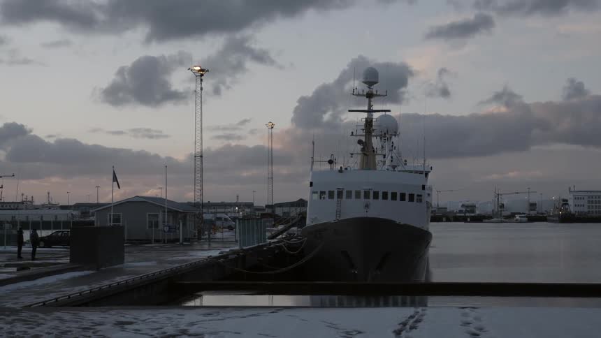 A large ship at a dock on a cloudy day at sunset