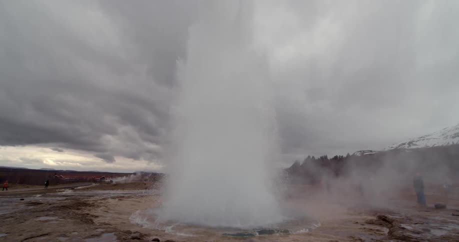 Steam rises and water erupts from a geyser