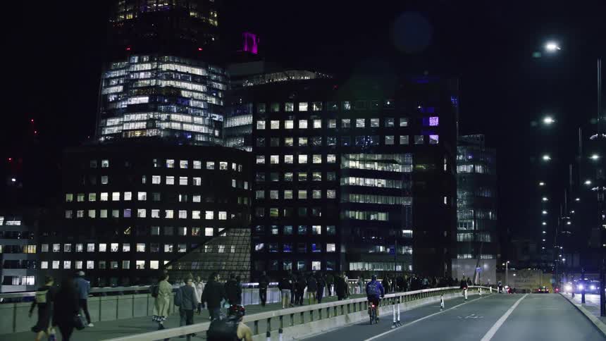 Busy street at night with skyscrapers around and pedestrians walking