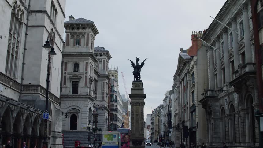 Statue of dragon stands in divided street between apartments and landmark buildings