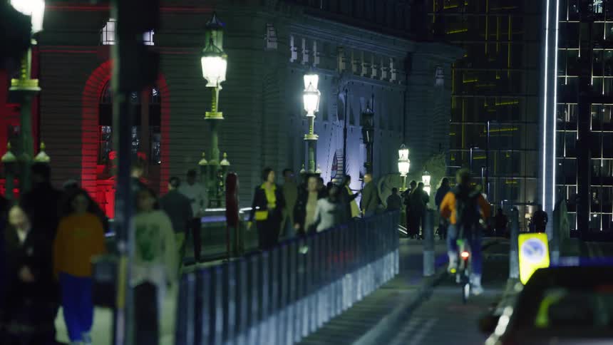 Panorama of a street at night with lampposts with several people walking in the middle of a metropolis