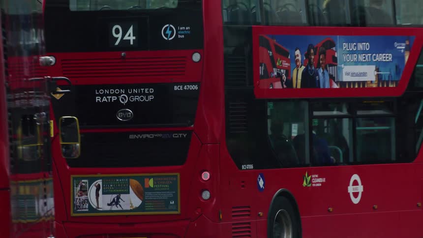 A red bus with several passengers inside on a street full of cars