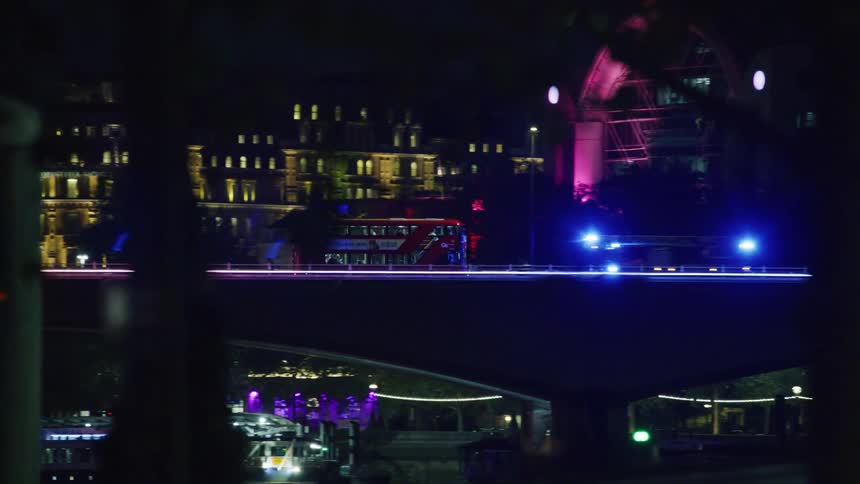 View of a public bus passing over an overpass at night