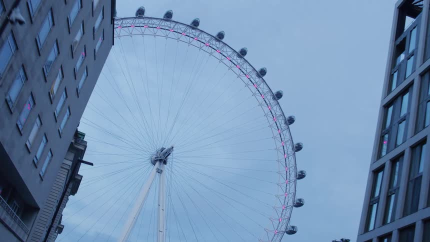 View of a huge ferris wheel in a morning with buildings around it in a metropolis