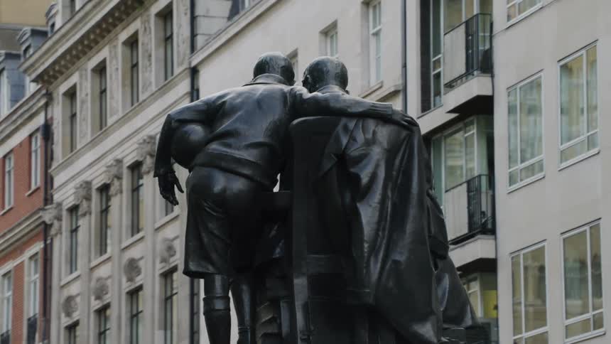 Sculpture of boy listening to man read sits in plaza between apartment buildings
