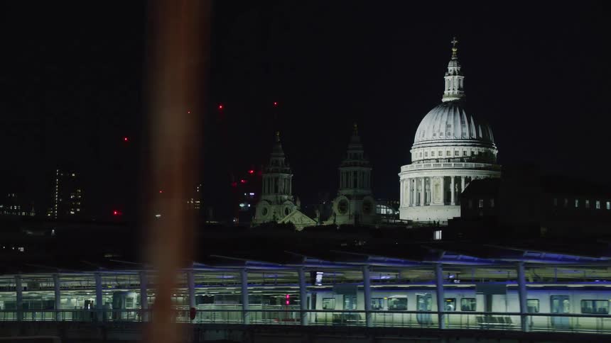 A capitol building in an urban area is viewed from a moving vehicle at night