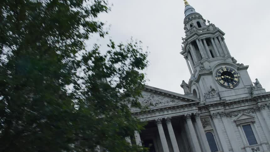 A classical building with two towers and a dome adorned with clocks and statues