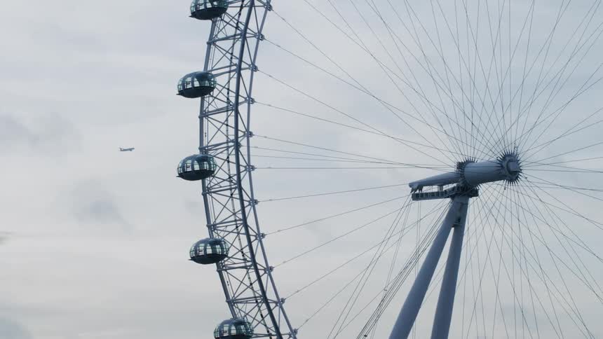 A ferris wheel with empty cabins on a cloudy day