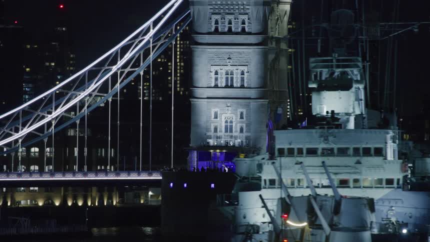 A naval ship sits near a bridge in the city