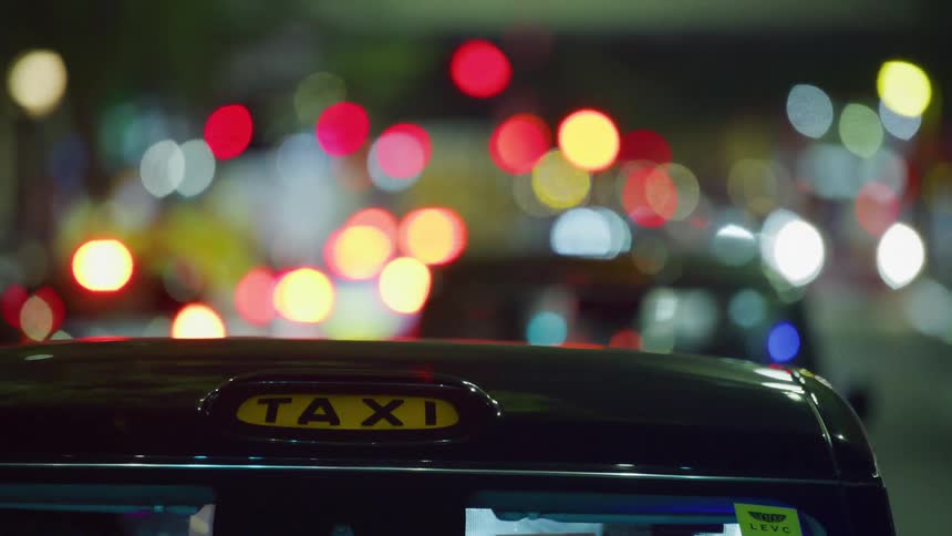 Closeup on the roof of a moving taxi at night through the city