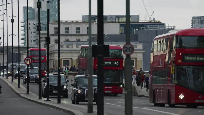 Pedestrians walk along sidewalk paralleling busy controlled access highway passing through the city