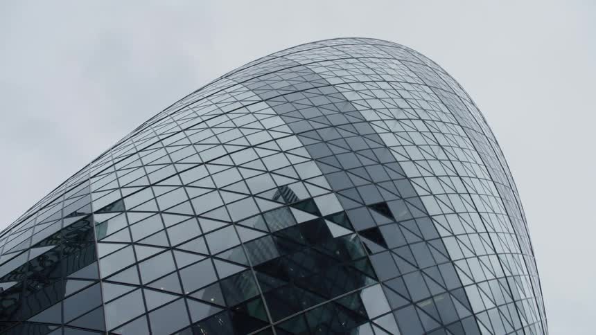 Rounded and modern exterior architecture all mirrored in glass of a building on a cloudy day