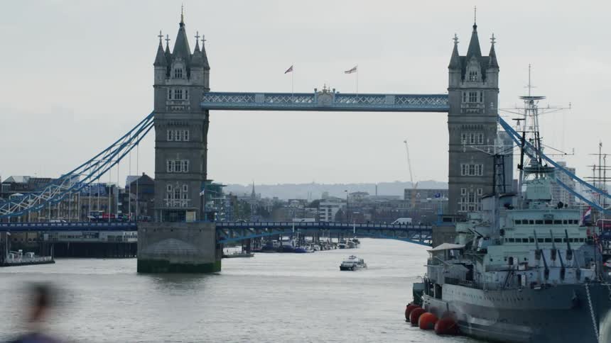 A naval vessel sits near an old bridge