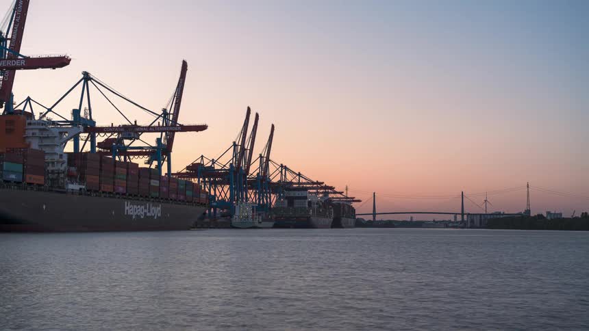 Timelapse of ships in a port with containers being unloaded as the day darkens