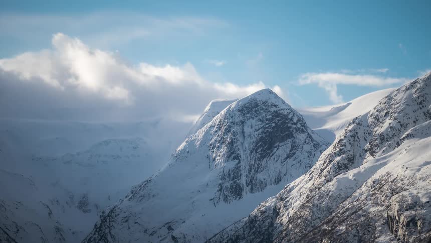 Mountain range covered in snow with clouds passing by in timelapse