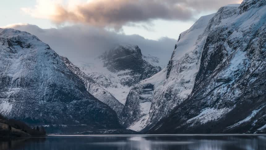 Clouds passing above snow covered mountains