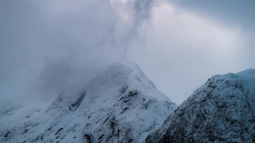 Top of a mountain range covered in snow during the day