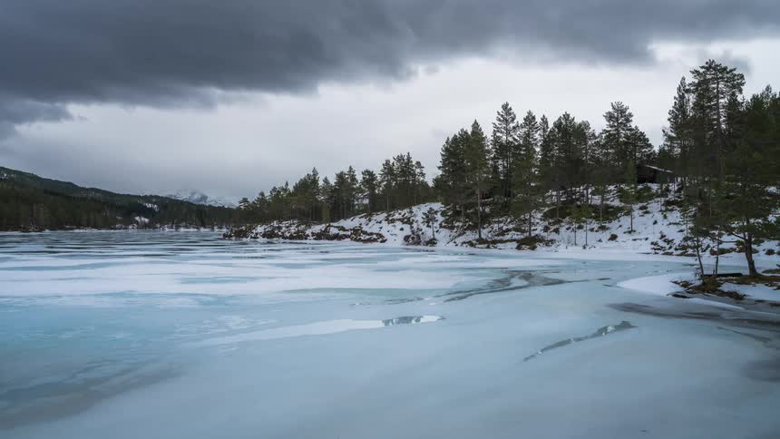 A clip of a frozen lake surrounded by woods